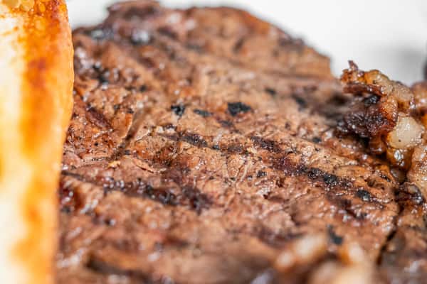 Close-up of a grilled steak with dark sear marks.