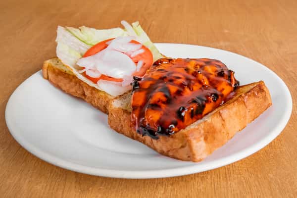 Grilled chicken sandwich served open-faced on toast with lettuce, tomato and onion.