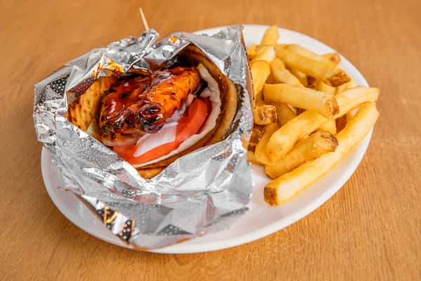 Foil-wrapped chicken gyro served with french fries and dipping sauce.
