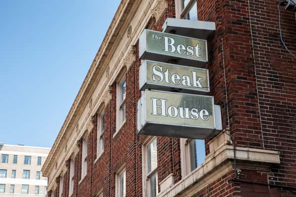 The Best Steak House sign projecting from the brick building, viewed from below.