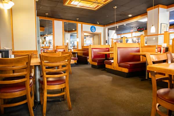 The Best Steak House dining room with wooden tables, chairs and red booths.