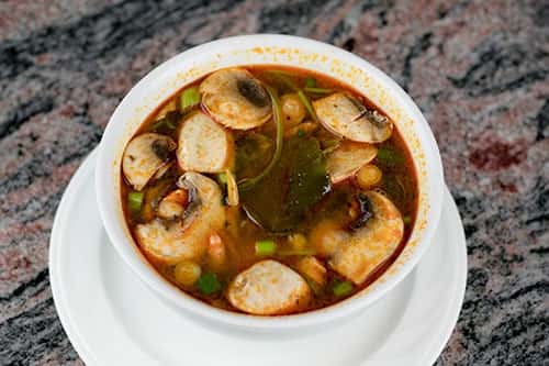 Hot & sour soup with mushrooms, lemon grass, galanga root, lime juice, kaffir lime leaves, & cilantro, with the meat of your choice below.