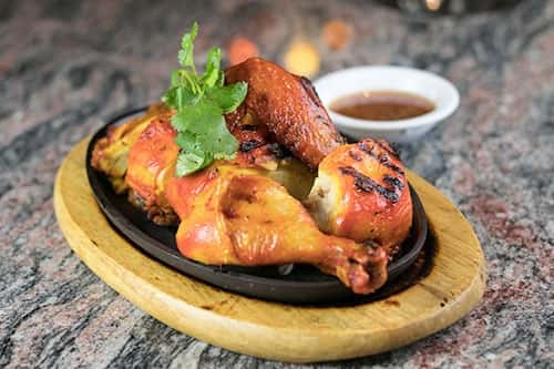 Thai Rama barbecue chicken with a spicy sauce on the side.