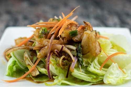 Shrimp lightly sautéed In lemon grass, mint and lime sauce, on top of a bed of lettuce.