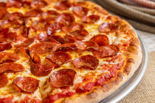 Close-up of a classic pepperoni pizza with a crispy crust and bubbling cheese, topped generously with curled pepperoni slices.