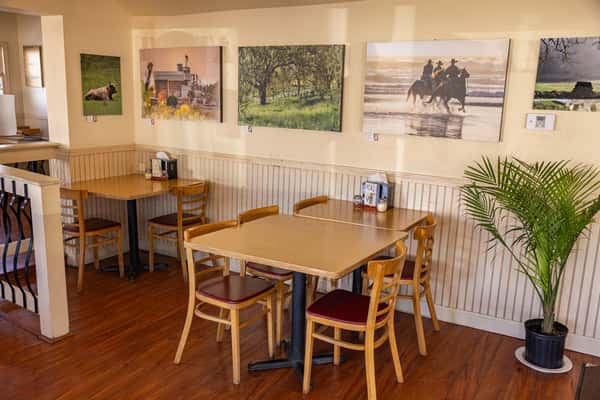 Cozy restaurant interior with wooden tables and chairs, cowboy-themed wall art, and a warm, rustic atmosphere.