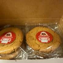 Individually wrapped large bakery cookies with branded labels inside a pastry box, highlighting freshly baked gourmet cookies prepared for takeout, gift orders, or specialty dessert catering.