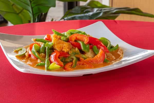 Crispy sweet and sour chicken stir-fried with red and green bell peppers and green beans in orange sauce, served on a modern white plate.