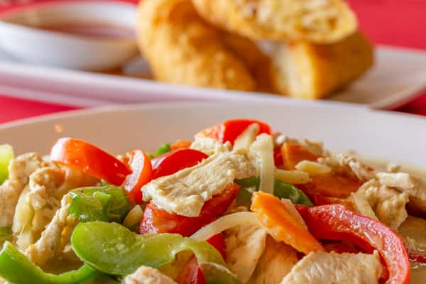 Crispy fried fish in red curry sauce topped with green beans and bell peppers, served on a modern white square plate.