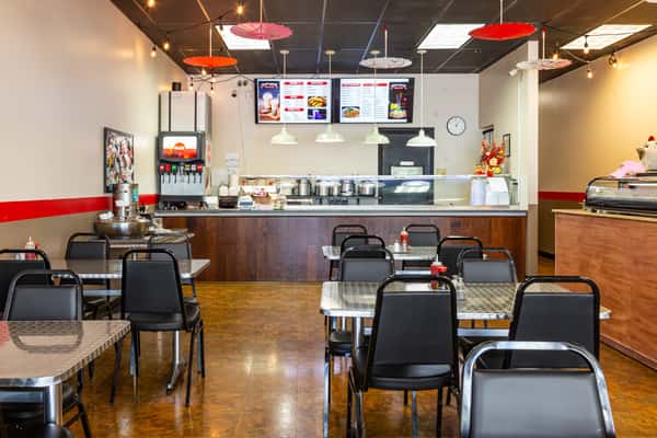 Interior view of Hot Wok restaurant featuring a casual dining setup with metal tables, black chairs, and hanging paper umbrellas—ideal for showcasing a cozy, welcoming Asian dining atmosphere.