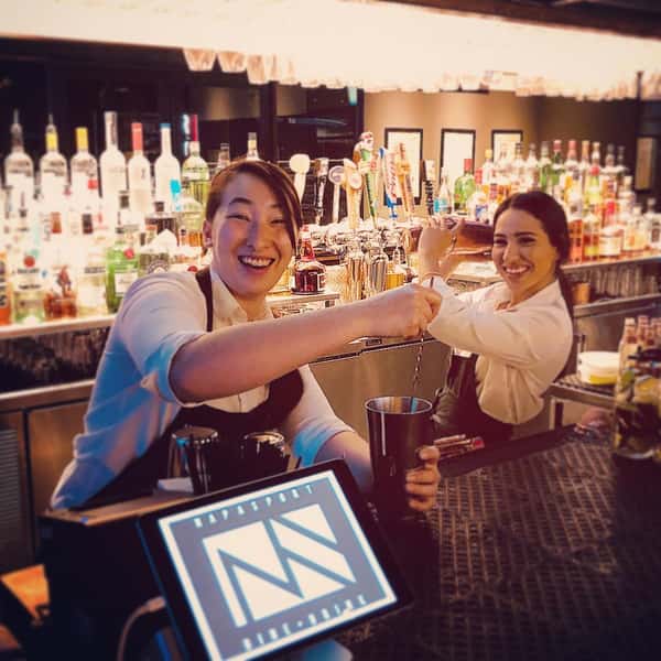 two bartenders posing for a photo behind the bar