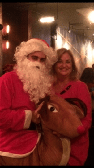a customer smiling with santa and a reindeer