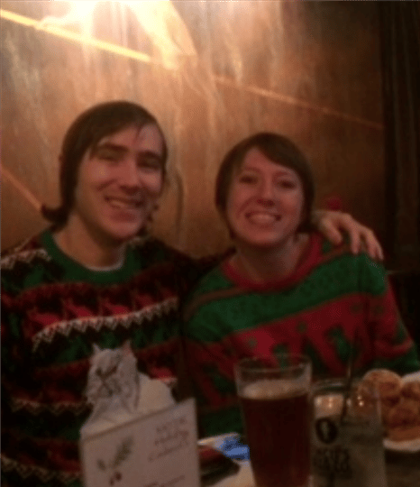 two customers smiling together while wearing ugly christmas sweaters