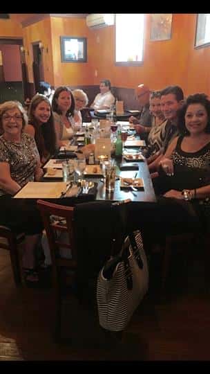 a big table of customers with their drinks and smiling