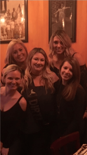 five women posing together and smiling