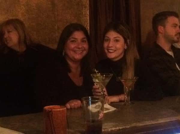 two women smiling together with their martinis