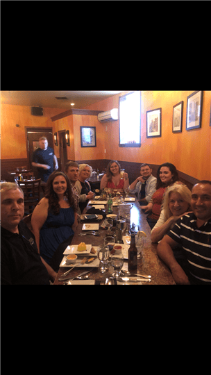 9 happy customers sitting at a table with food