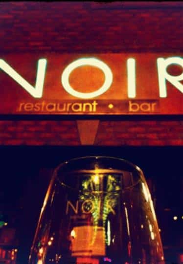 logo of noir with a glass of wine