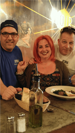 a group of 3 customers smiling at the bar with their appetizers