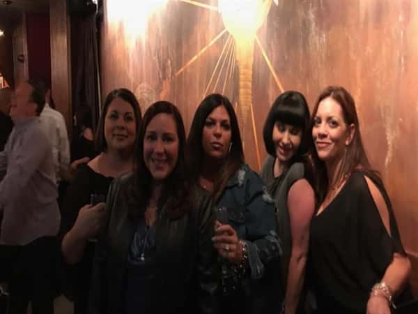 five customers posing against a wall