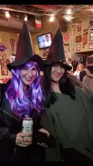 two customers smiling together while wearing witch hats