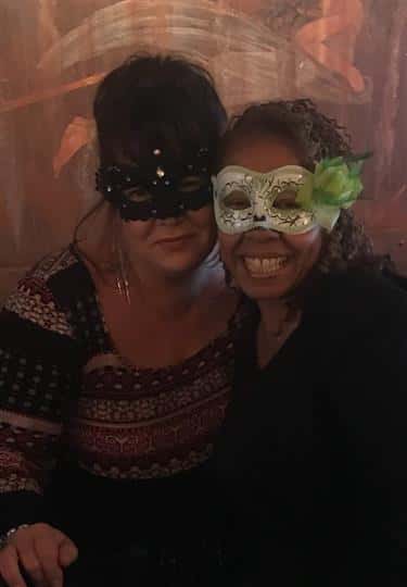 two women smiling while wearing masquerade masks