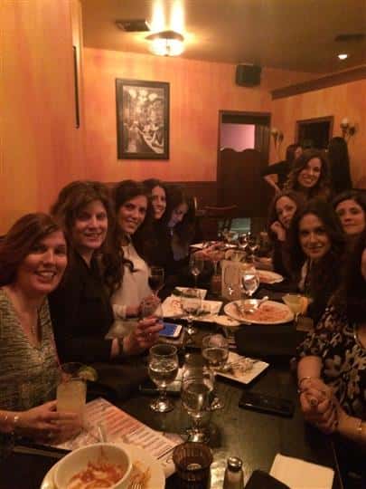 10 women smiling around their table