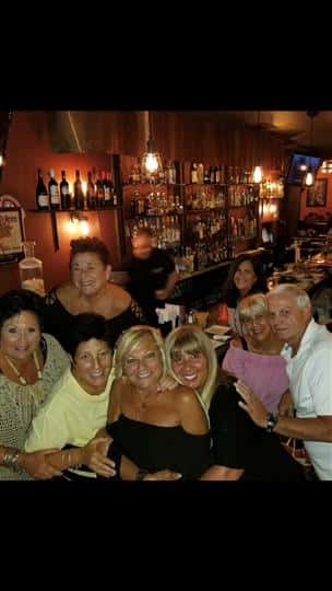 7 customers smiling together at the bar