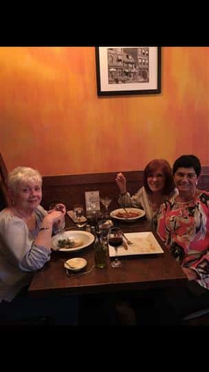 three happy women smiling at their table while eating