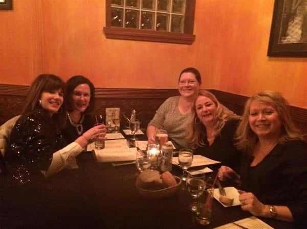 5 friends smiling at their table with menus