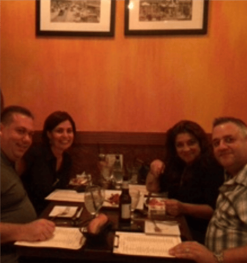 four friends smiling at their table with drinks
