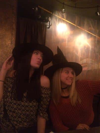 two girls posing while wearing witch hats