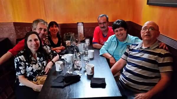 group of six friends smiling at their table