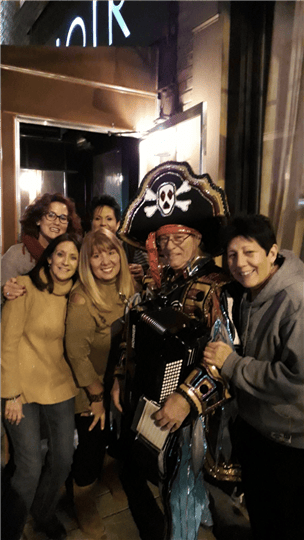five customers smiling and posing with a man dressed like a pirate