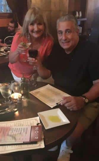 a couple smiling with a glass of wine and a martini