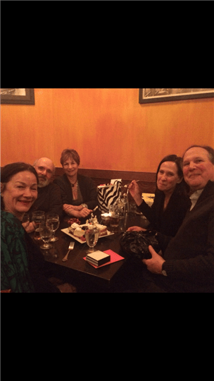 five friends smiling together around a table
