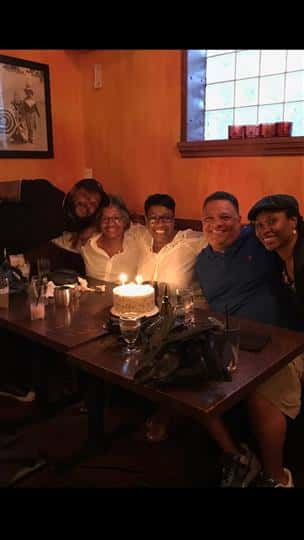 five family members smiling with a lit birthday cake
