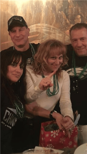 four friends smiling together while wearing green beads
