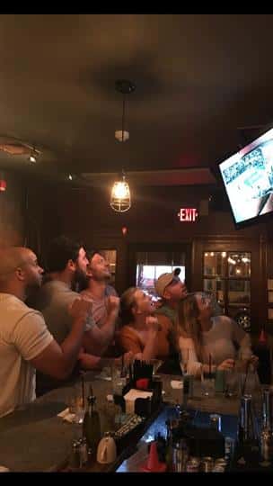 a group of friends watching a game on the tv at the bar