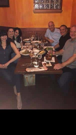 a group of six people smiling at their table with food