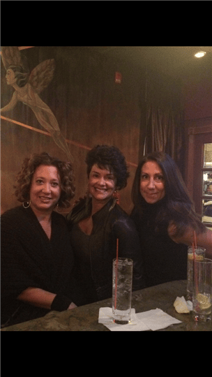 three women smiling and posing by the bar