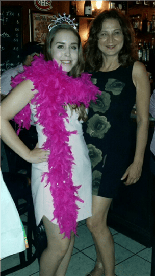 a women posing with a birthday girl who is wearing a tiara and boa