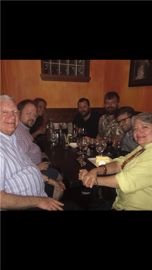 7 customers smiling around a table