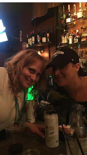 two friends smiling together with their drinks at the bar