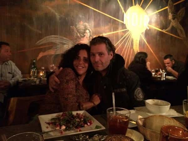 a couple hugging at the bar with their drinks and a plate of salad