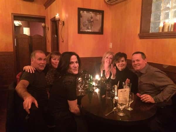 six friends smiling around a table