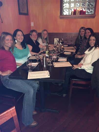 7 women smiling at a table with glasses of wine