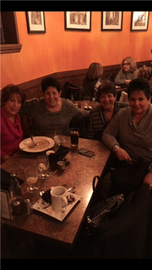 a group of four friends smiling at their table