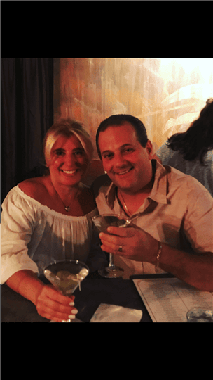 a man and woman smiling and holding their martinis
