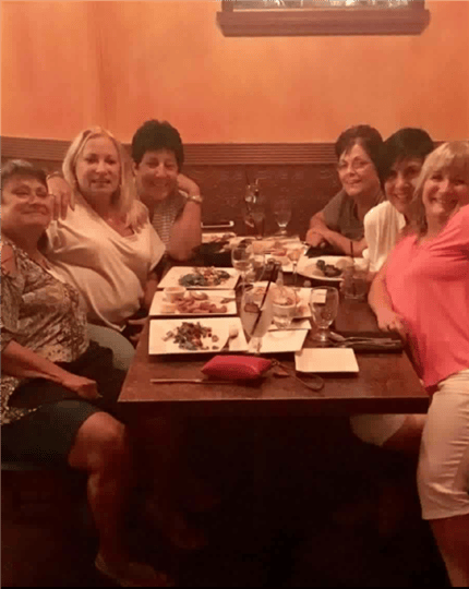 six women smiling at their table and having fun